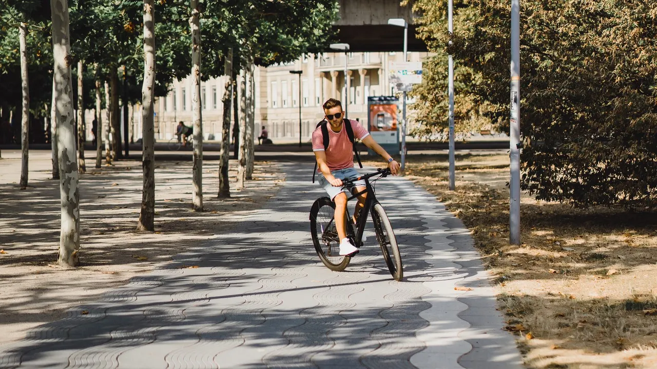 Ciclista pedalando em uma ciclovia arborizada na cidade