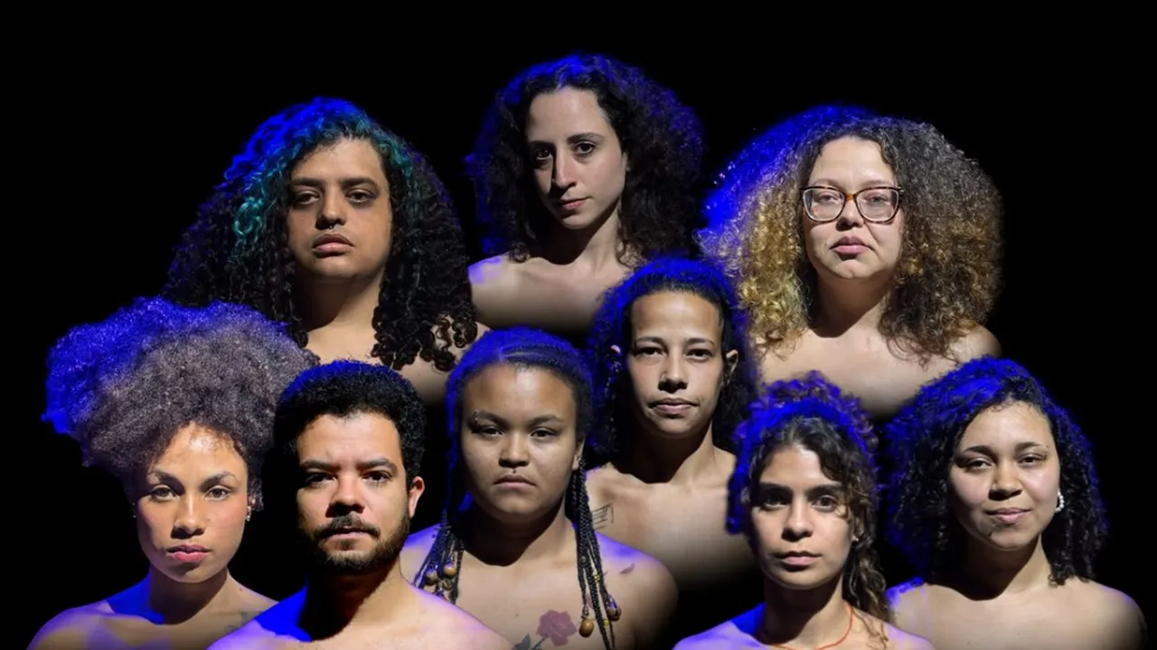 Nove integrantes do espetáculo reunidos sob iluminação azul diante de fundo preto