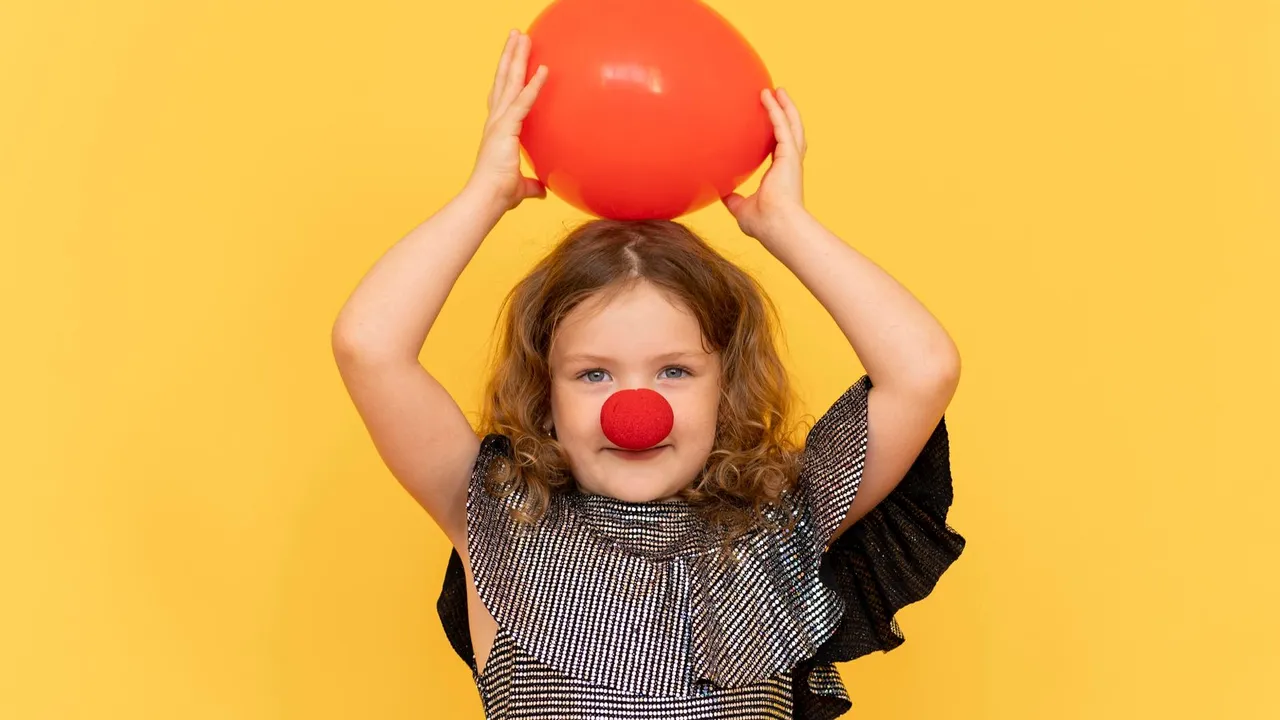 Menina sorridente usando nariz vermelho de palhaço