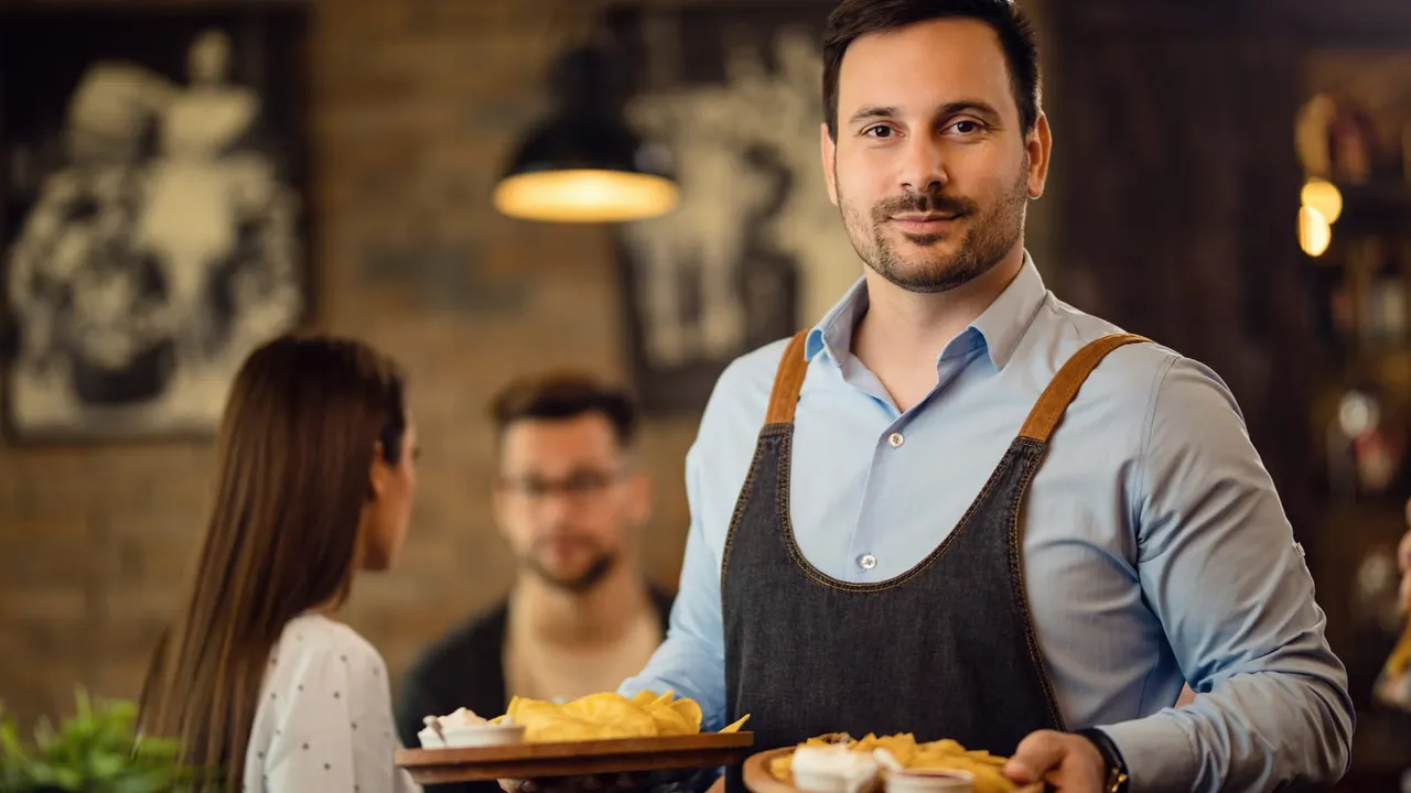 Garçom em um restaurante segurando duas bandejas com pratos de comida