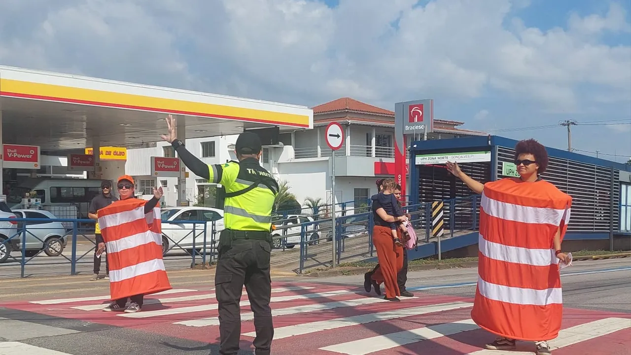 Agentes de trânsito e pessoas fantasiadas de cone orientam pedestres em uma faixa de pedestres em Sorocaba