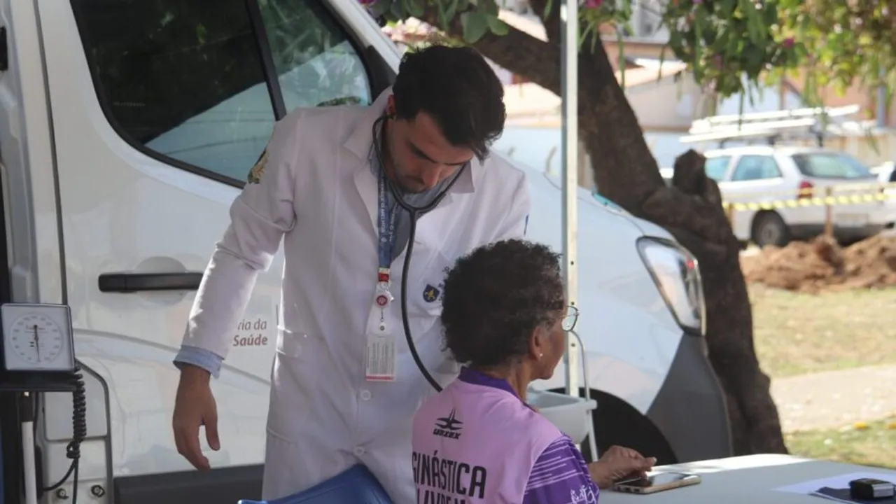 Profissional de saúde com estetoscópio atende uma mulher ao lado da clínica móvel do Médico na Praça