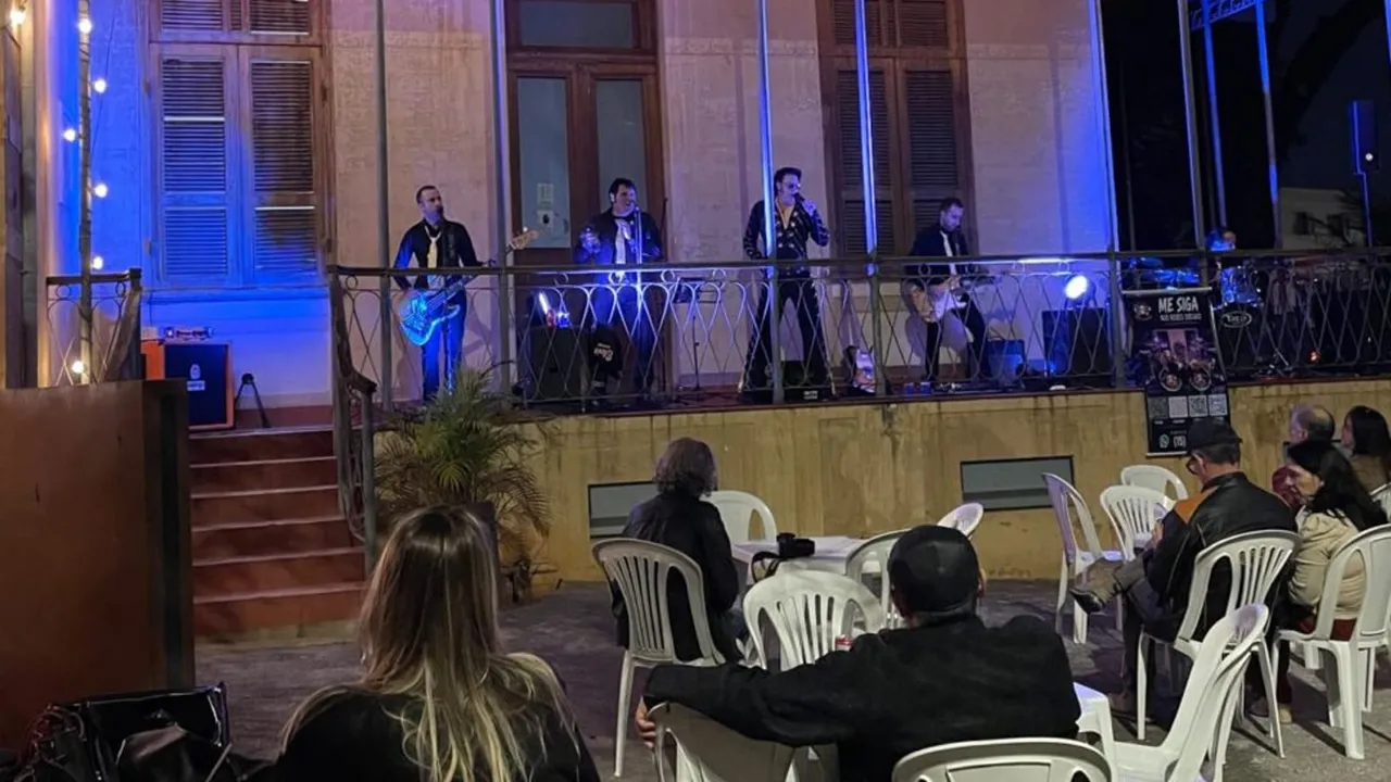 Banda se apresentando na sacada iluminada do Chalé Francês diante do público