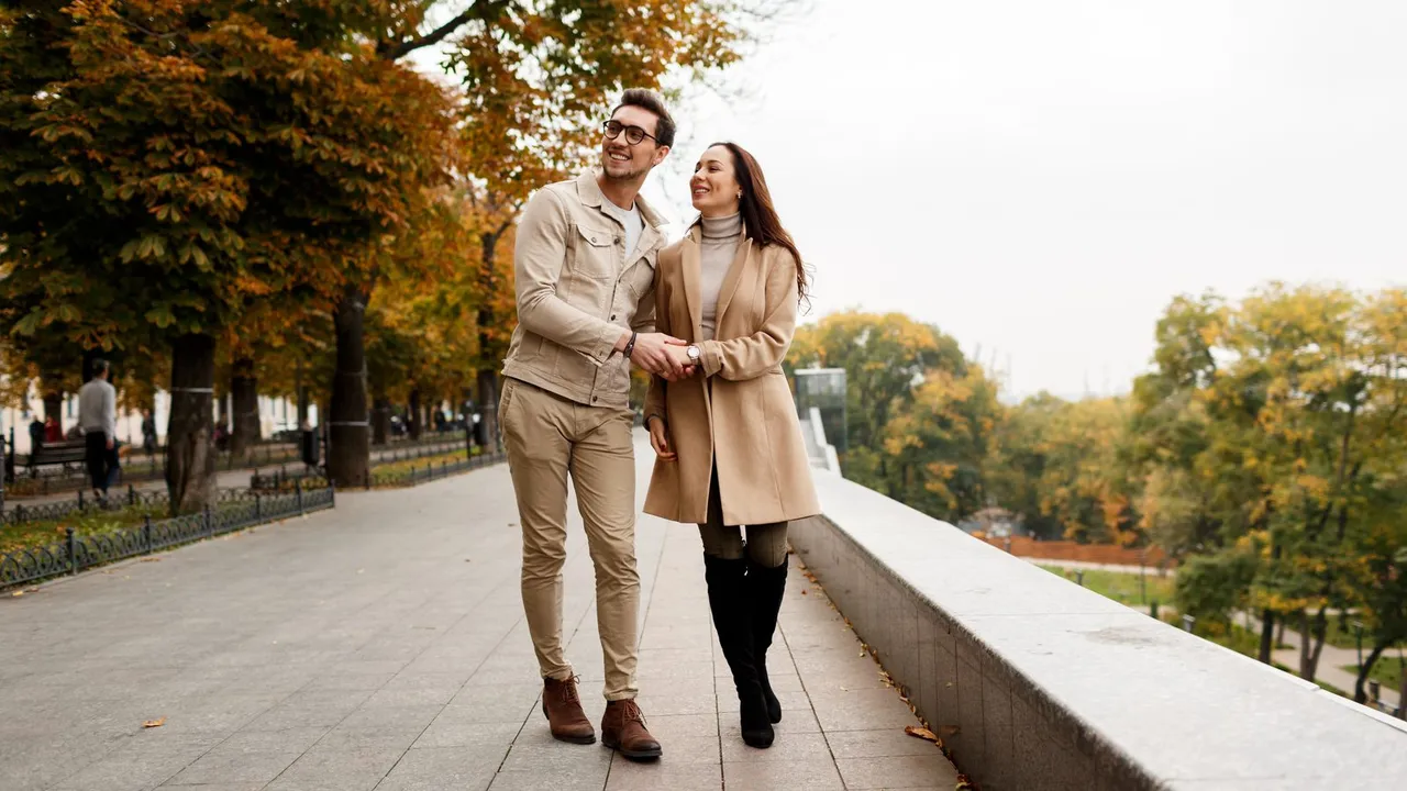 Casal caminhando em uma alameda arborizada de um parque urbano